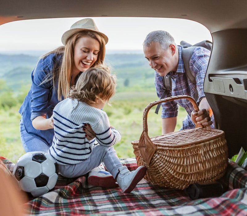 a mum and dad lift a child from out of the car